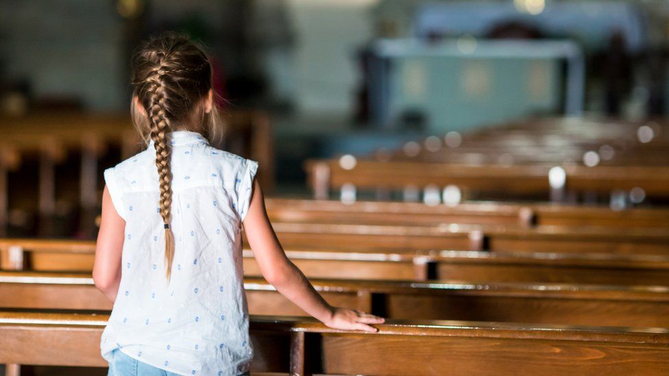 Girl standing in pews of a church