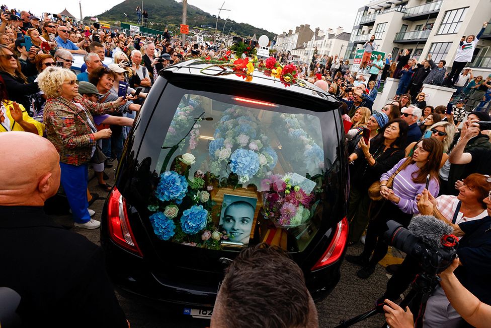 A hearse carrying the coffin of late Irish singer Sinead O'Connor passes by during her funeral procession