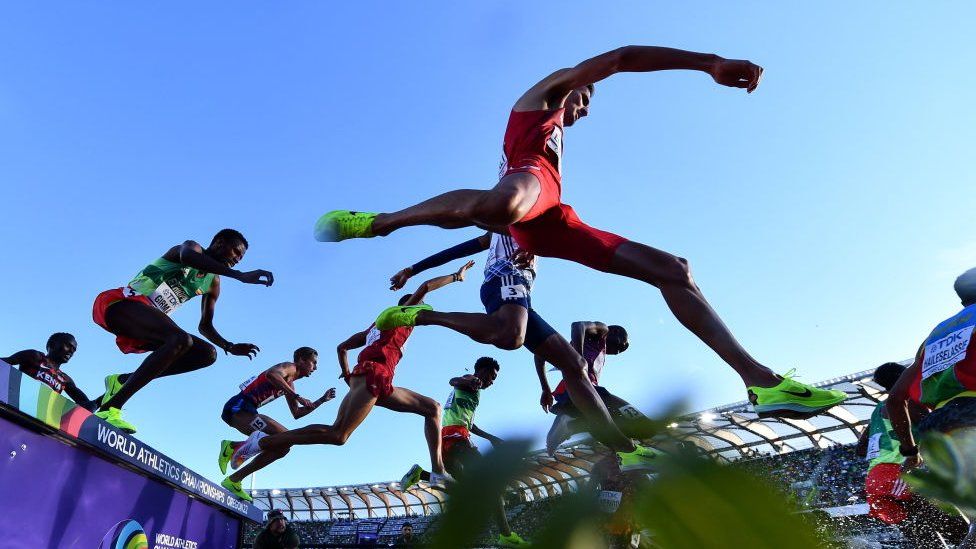 Athletes mid-way in the air doing steeplechase
