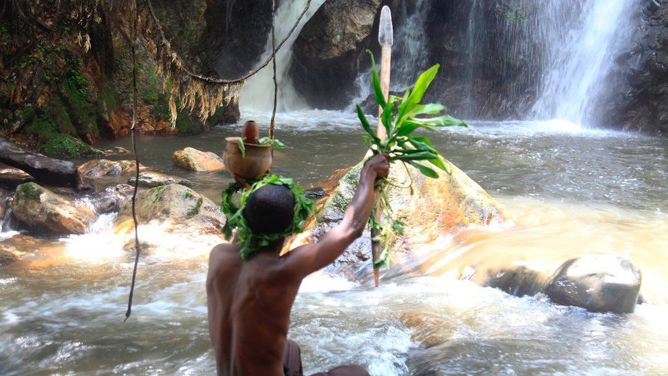 A spiritual leader performs a ritual at the Ekisalhalha kya Kororo waterfall