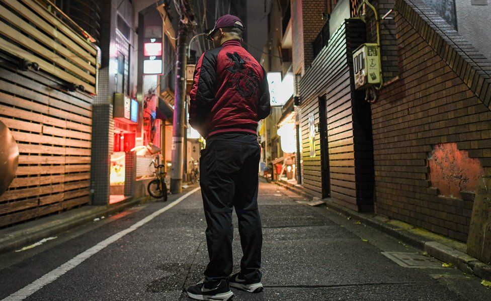 Изображение репортера Би-би-си под прикрытием, сфотографированного сзади на улице Токио
