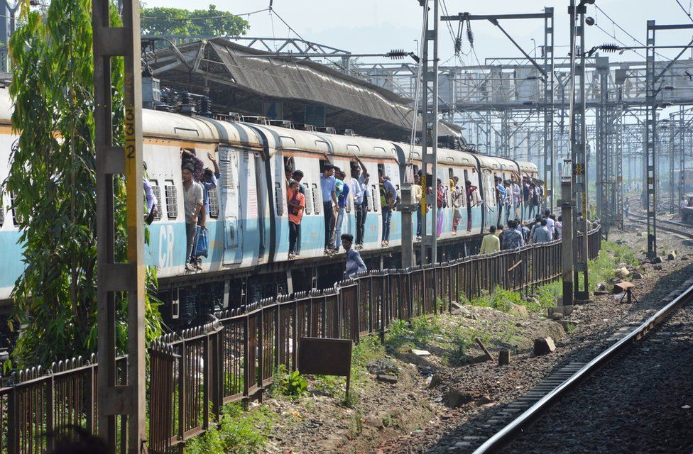 People hang out of coaches in Mumbai's local trains