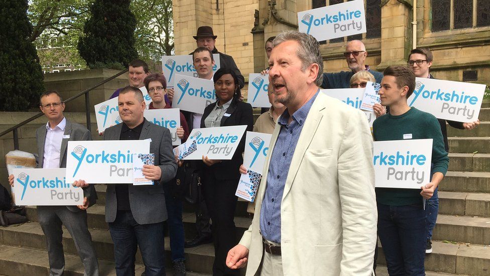 People with Yorkshire Party placards standing on steps