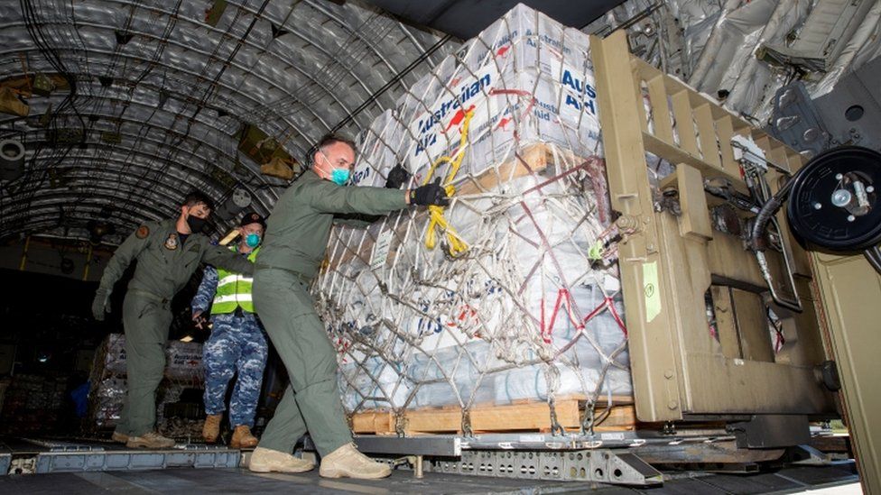 Australian Defence Forces members unload humanitarian assistance and engineering equipment from an aircraft at Fua"amotu International Airport