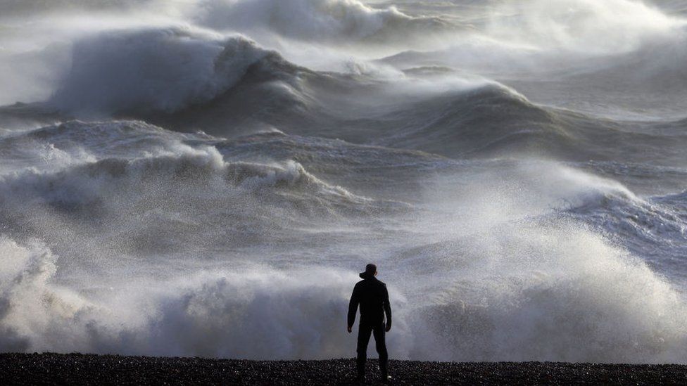 A person looks out towards the waves crashing on the shore in Newhaven during Storm Henk.