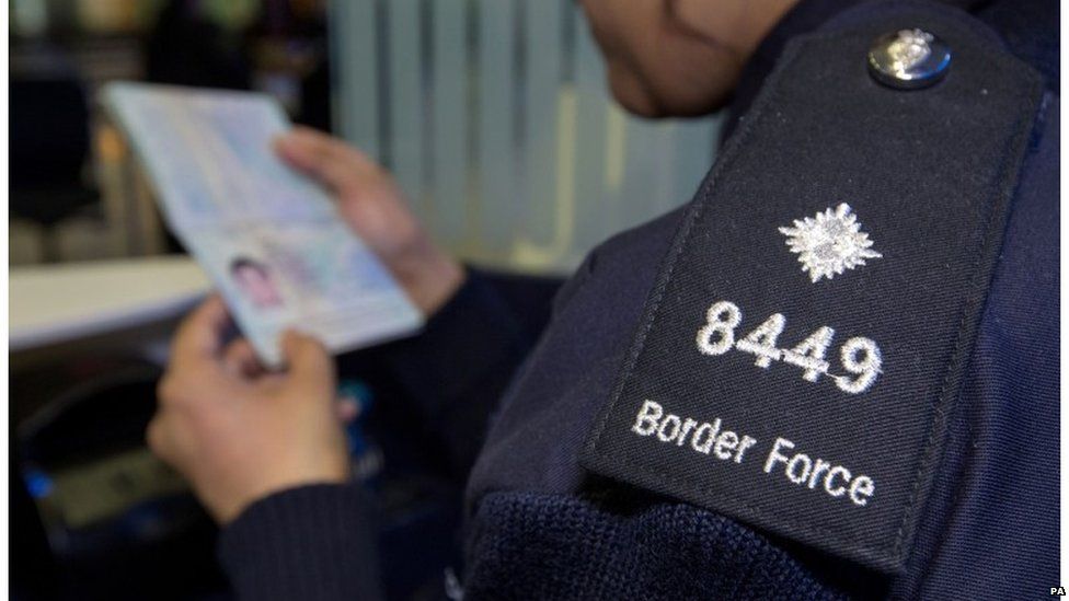 Border Force official looking at passport