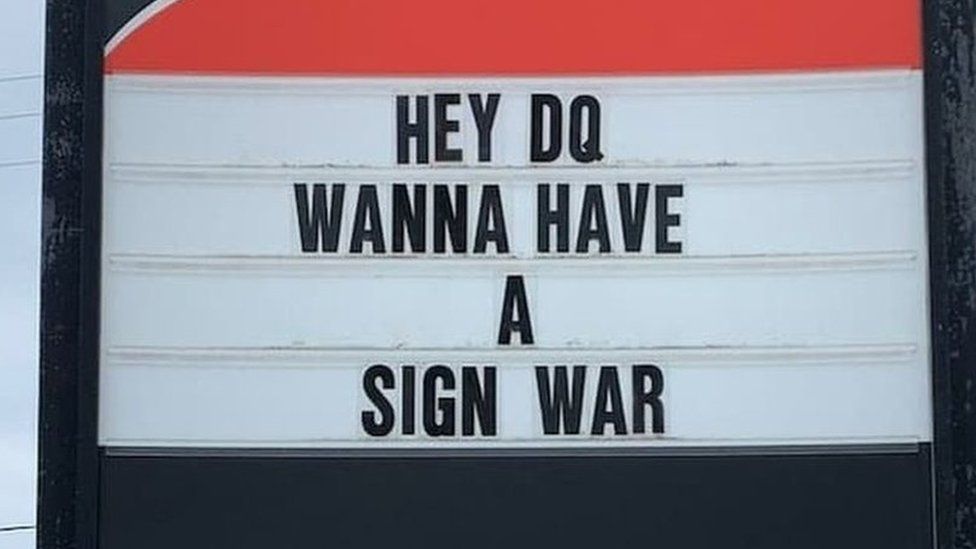 A sign reads 'Hey DQ, Wanna have a sign war'