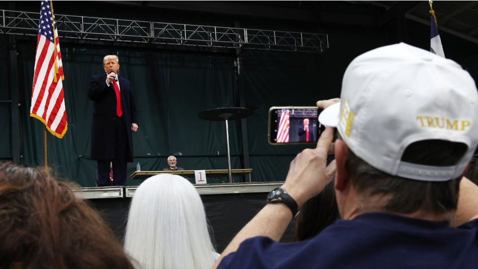 A supporter films Donald Trump at a caucus in Iowa