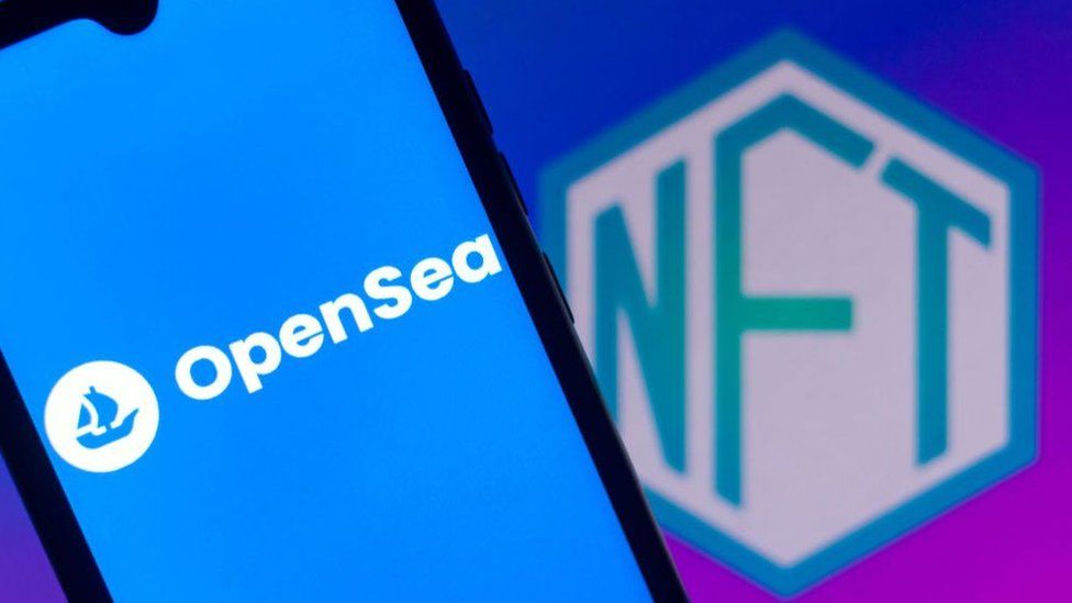 На этой фотографии изображен логотип OpenSea, отображаемый на смартфоне с логотипом NFT (невзаимозаменяемый токен) на заднем плане.