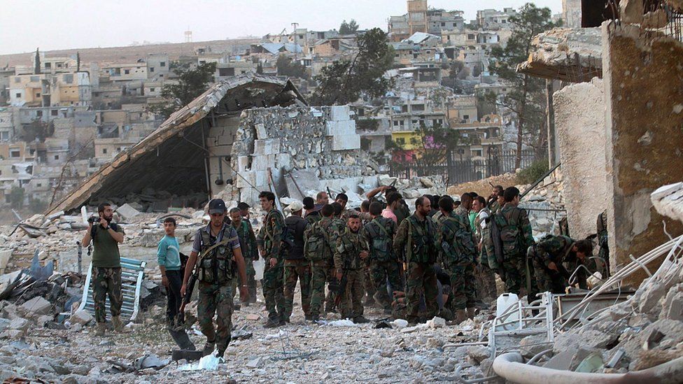 Syrian government forces walk through the Handarat Palestinian refugee camp, north of Aleppo, on 2 October 2016