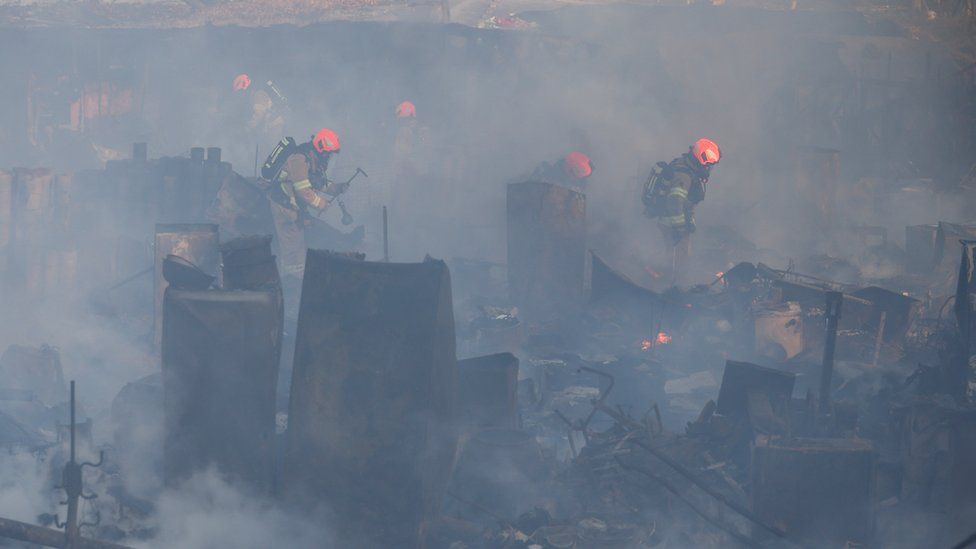 Firefighters stamp out small fires in the aftermath of a fire in a Seoul slum