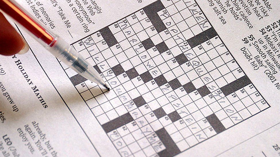 A person filling out a crossword puzzle