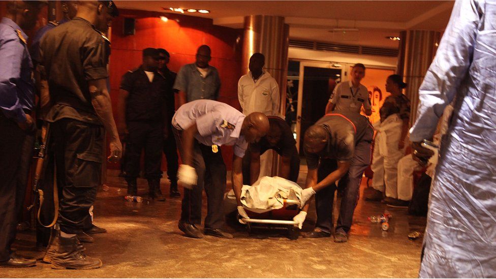 Mali security personal pick up the lifeless body of a victim inside the Radisson Blu hotel after an attack by gunmen on the hotel in Bamako, Mali, Friday, Nov. 20, 2015