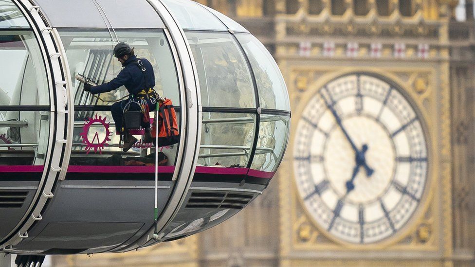 A window cleaner scrubs the London Eye pods