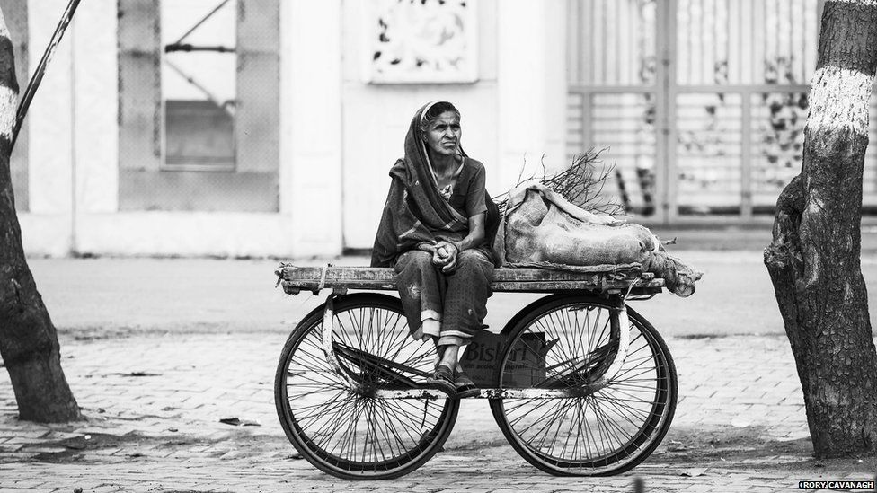 A woman sitting on a car in an Agra city street