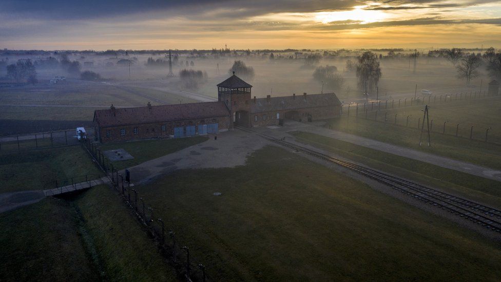 The sun rises over the early morning mist blanketing the barbed wire electrified fence and the Death Gate the Auschwitz II-Birkenau extermination camp on December 18, 2019