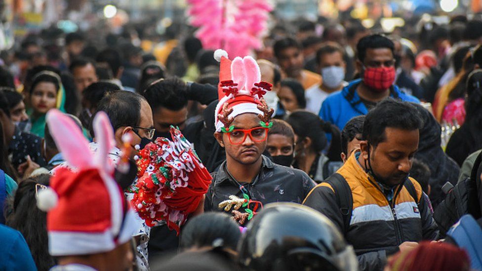 Мужчина продает шляпы Санта-Клауса и другие рождественские аксессуары на многолюдном рынке в Калькутте