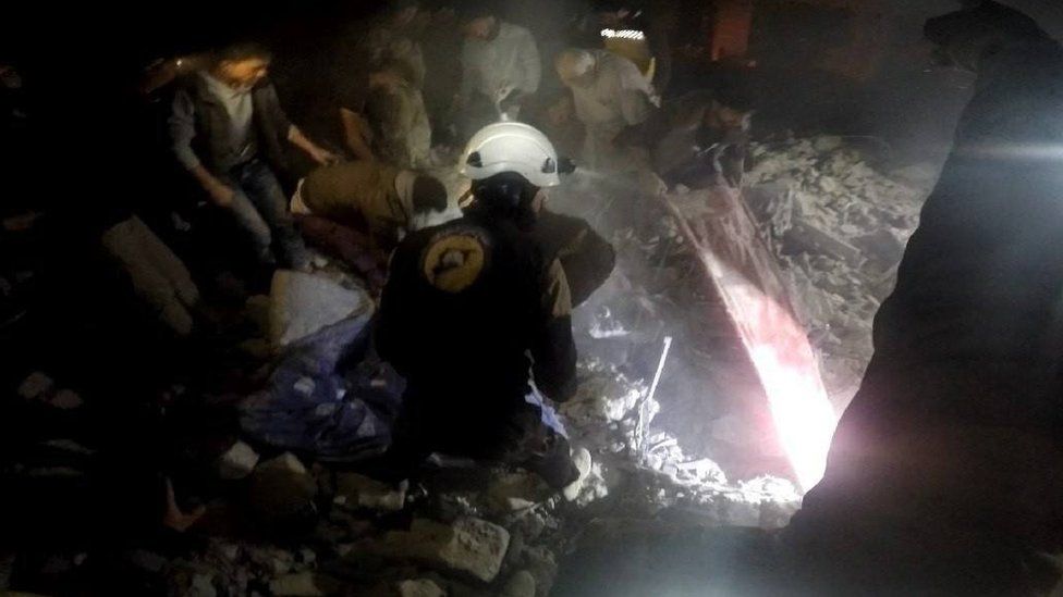 Photo posted by the Syria Civil Defence, also known as the White Helmets, purportedly showing rescue workers after air strikes on Maarshurin, in the Syrian province of Idlib (20 December 2017)