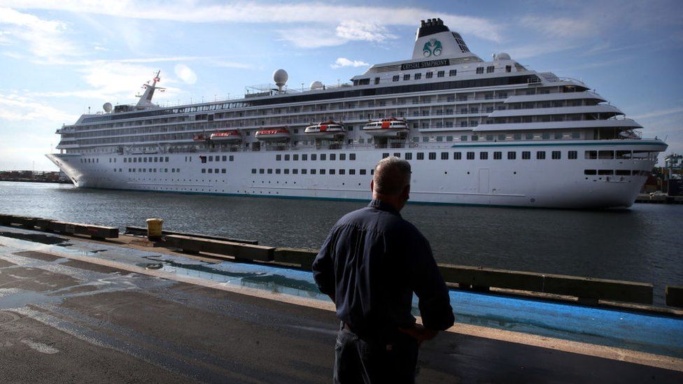 Пешеход наблюдает, как круизный лайнер Crystal Symphony прибывает в круизный порт Флинн в Бостоне, Массачусетс, 18 августа 2021 г.