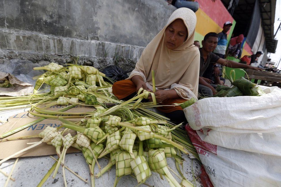 An Acehnese woman prepares ketupat, a type of rice dumpling packaged in palm leaves, in the lead up to Eid al-Fitr at a traditional market in Banda Aceh, Indonesia, 13 June 2018