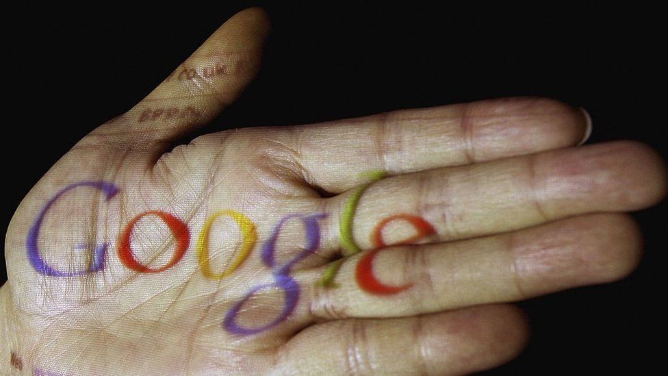 The Google logo is seen projected onto the palm of a hand on