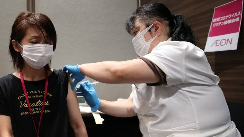 A staff of Japan"s supermarket group Aeon receives a dose of the Moderna vaccine