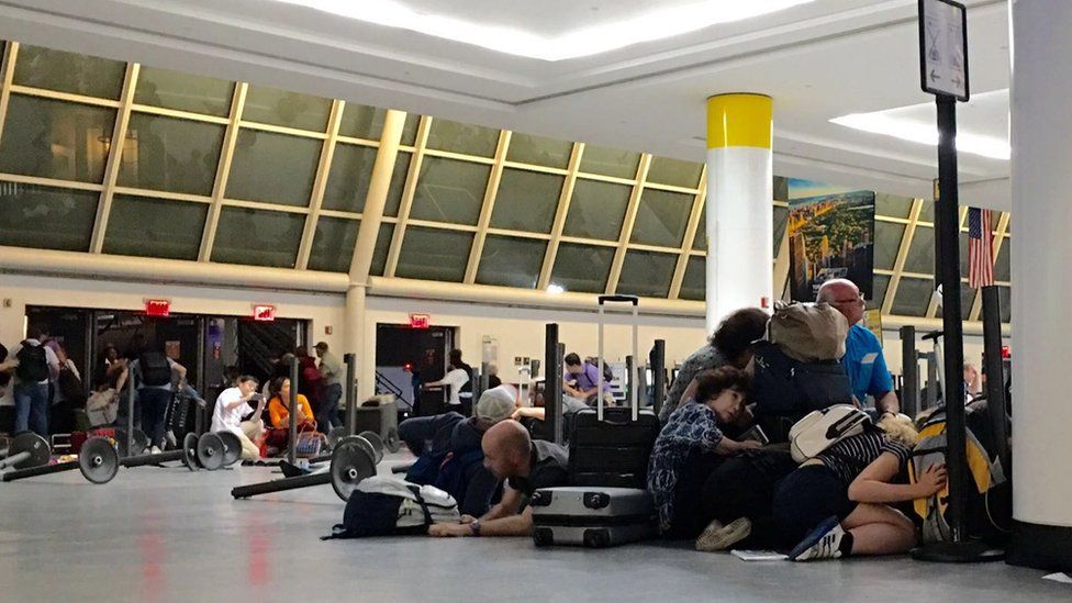 Passengers on the ground in the immigration area of JFK airport, 15 August