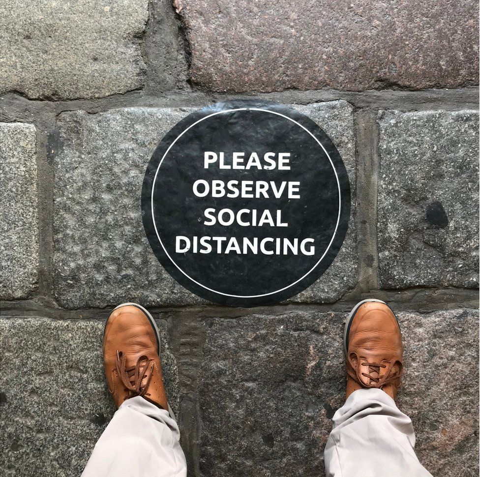 Знак на земле, призывающий людей соблюдать социальное дистанцирование