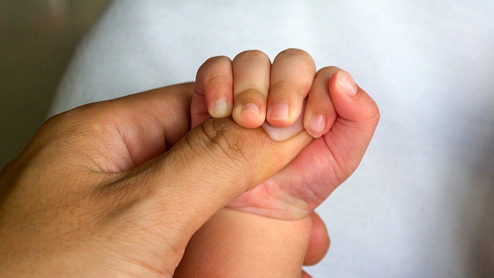 Mother holds baby's manus  (close up)