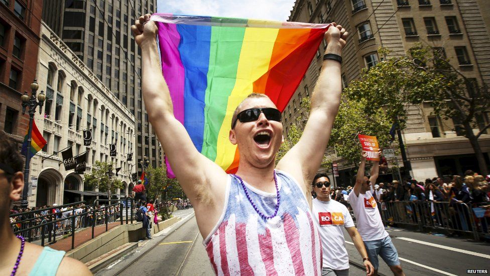 A man waves a rainbow flag while marching in the San Francisco gay pride parade - 28 June 2015
