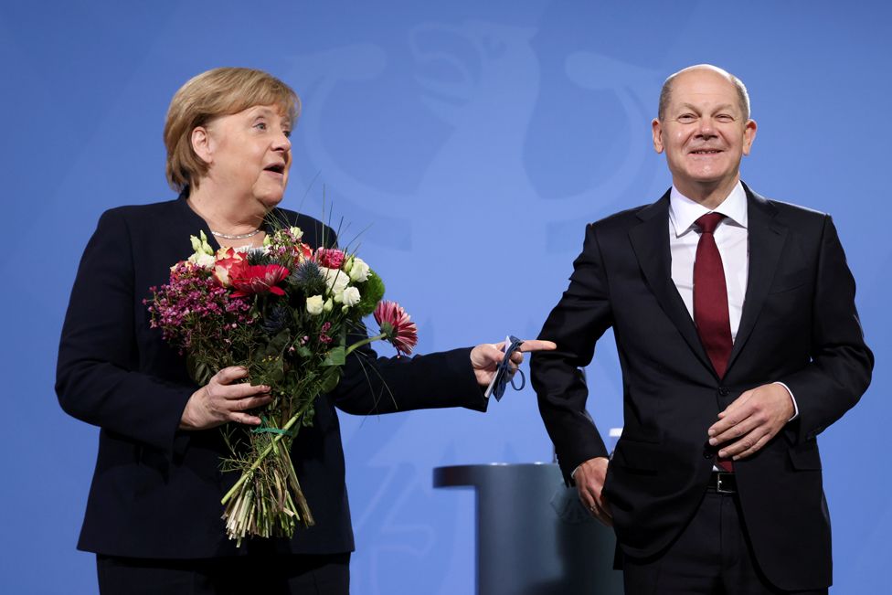 Former German Chancellor Angela Merkel holds flowers as she hands over the chancellery to her successor, the newly appointed Olaf Scholz at the Chancellery in Berlin, Germany, 8 December 2021.