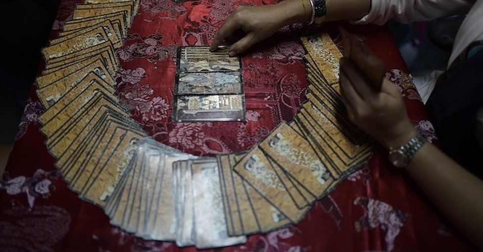 A fortune teller uses tarot cards to predict the future of a woman at a Buddhist temple in Bangkok