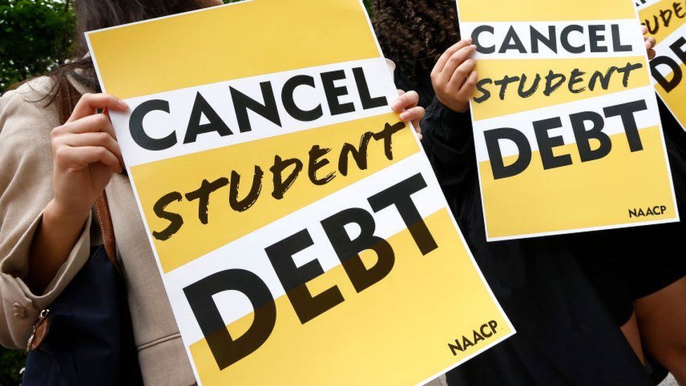 People hold up Cancel Student Debt signs