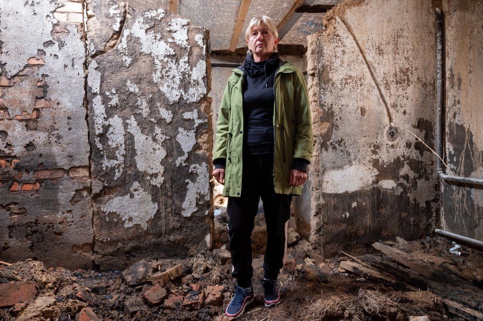 Liubov Smyrnova standing in her destoyed home