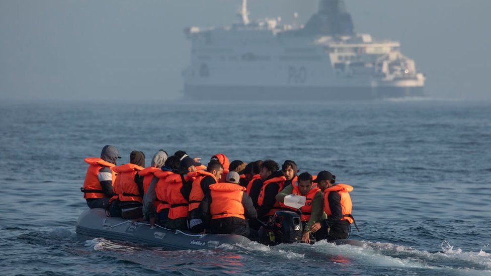 An inflatable craft carrying migrant men, women and children crosses the shipping lane in the English Channel