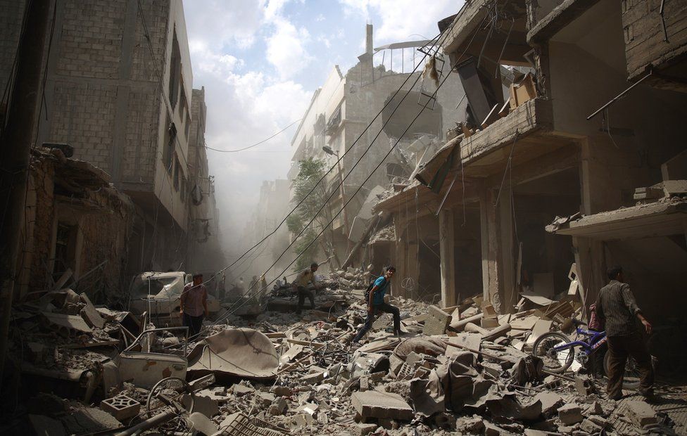 Syrians walk amid the rubble of destroyed buildings following reported air strikes by regime forces in the rebel-held area of Douma, east of the capital Damascus, on August 30, 2015
