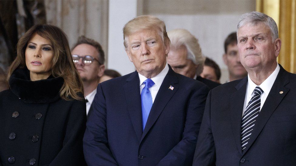 President Donald Trump and first lady Melania Trump stand with Franklin Graham during a ceremony