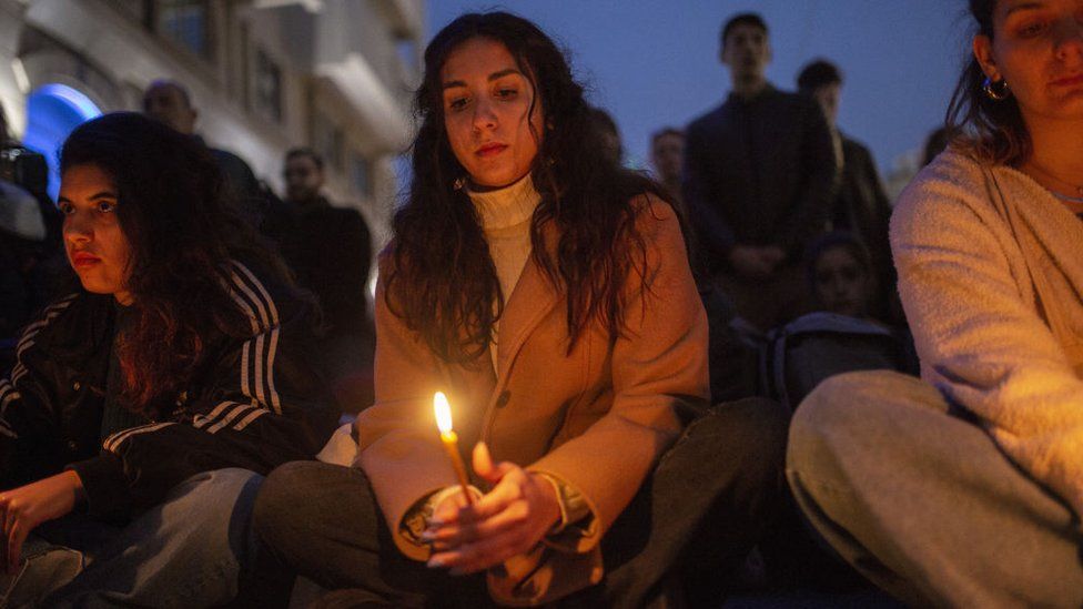 Protesters light candles outside the Hellenic Train offices in Athens on 1 March
