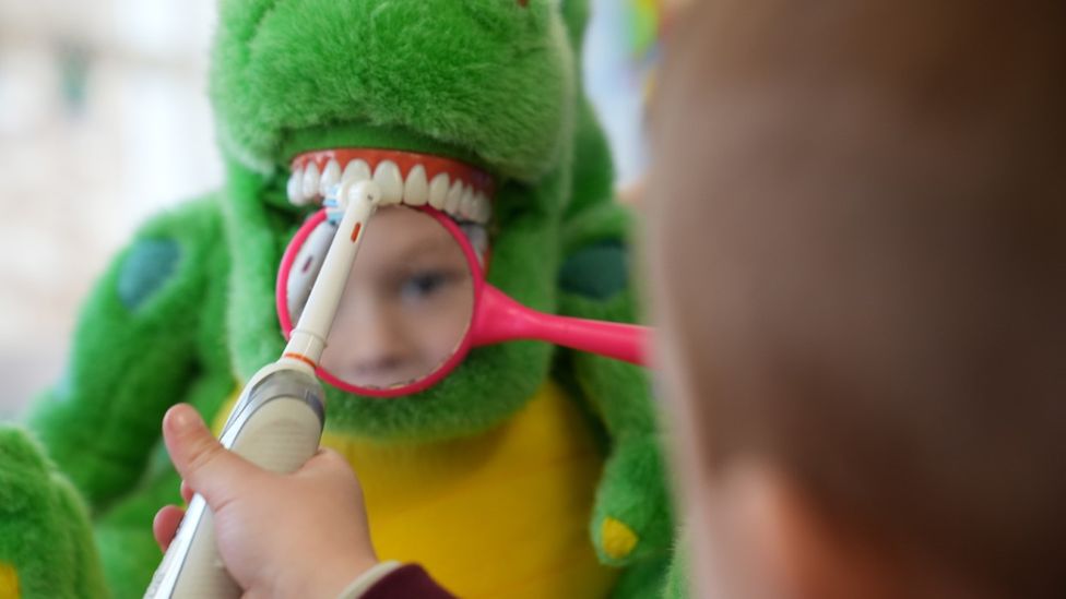 Child brushing a dinosaur's teeth