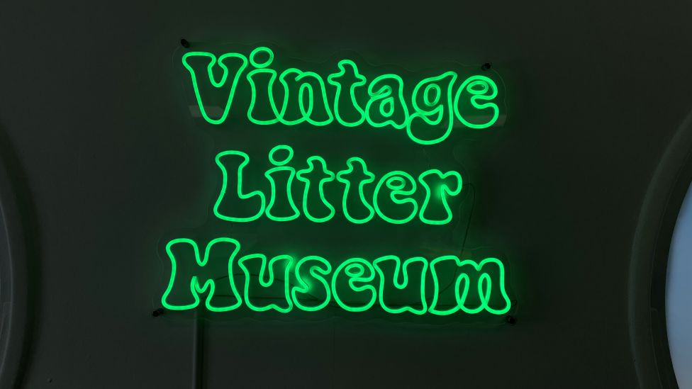 A neon green sign saying Vintage Litter Museum