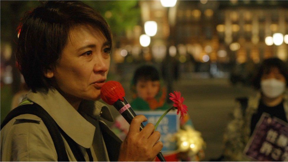 Минори Китахара держит микрофон и цветок на демонстрации цветов в Токио