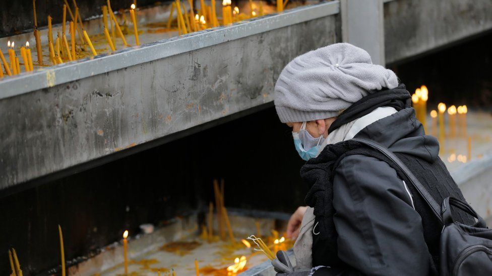 An orthodox believer lights a candle for the late Serbian Patriarch Irinej in Belgrade, Serbia, 21 November 2020.