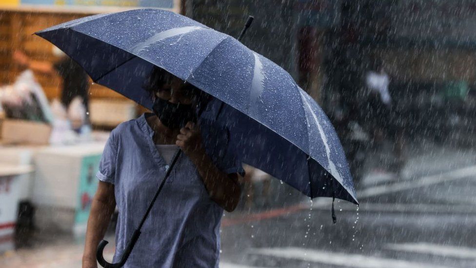 A woman walks with an umbrella during heavy rain near Su-ao port in Yilan as Typhoon Haikui makes landfall in eastern Taiwan on September 3, 2023.