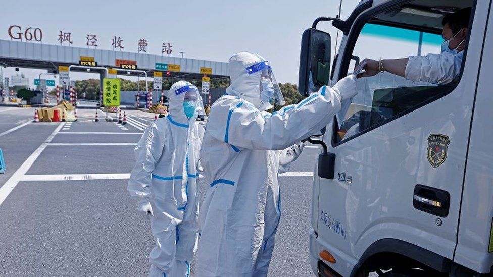 A police officer checks a truck driver's COVID-19 nucleic acid test result at an expressway toll station on April 3, 2022 in Shanghai, China.