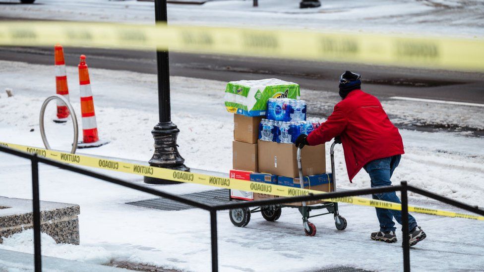 A delivery driver pushes a cart full of supplies down an icy sidewalk on February 11, 2021 in Louisville, Kentucky