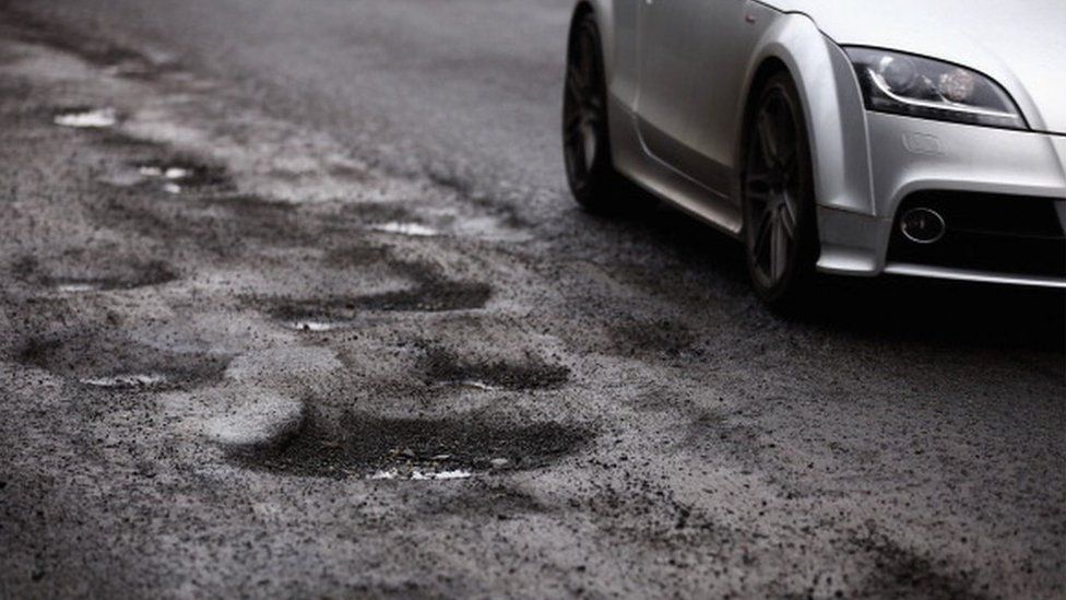 A car driving past potholes in the road