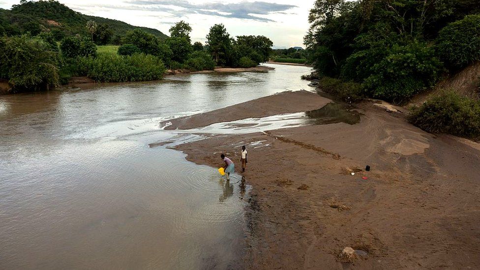 Two people fetch water from a river on the outskirts of Siachilaba village, Binga district in Matabeleland North Province, Zimbabwe, on January 24, 2017