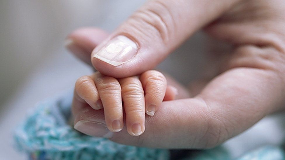 Mother holding premature baby's hand