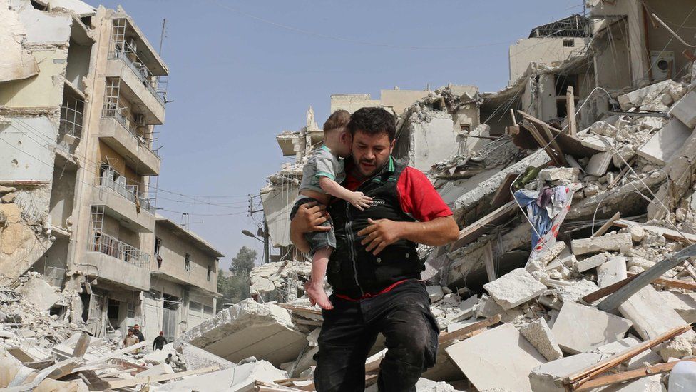 A Syrian man carries a baby after removing him from the rubble of a destroyed building following a reported air strike in the Qatarji neighbourhood of the northern city of Aleppo on 21 September
