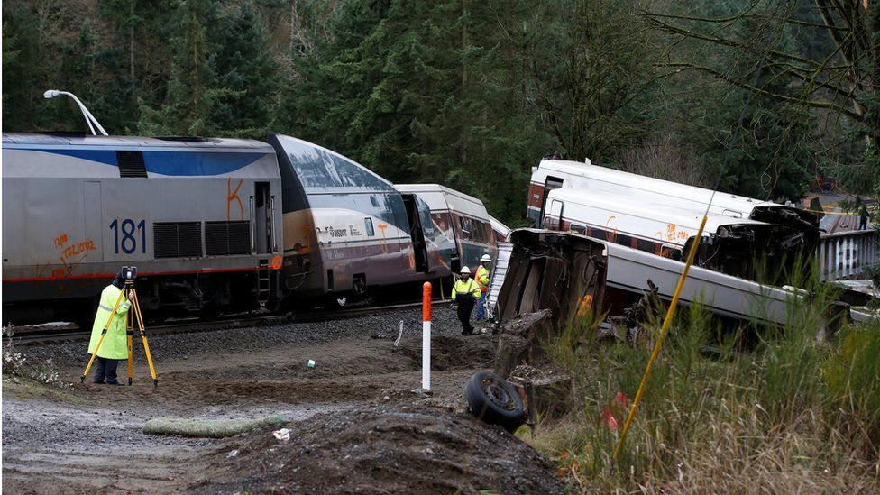 Investigators are seen working at the scene, with carriages off the rails